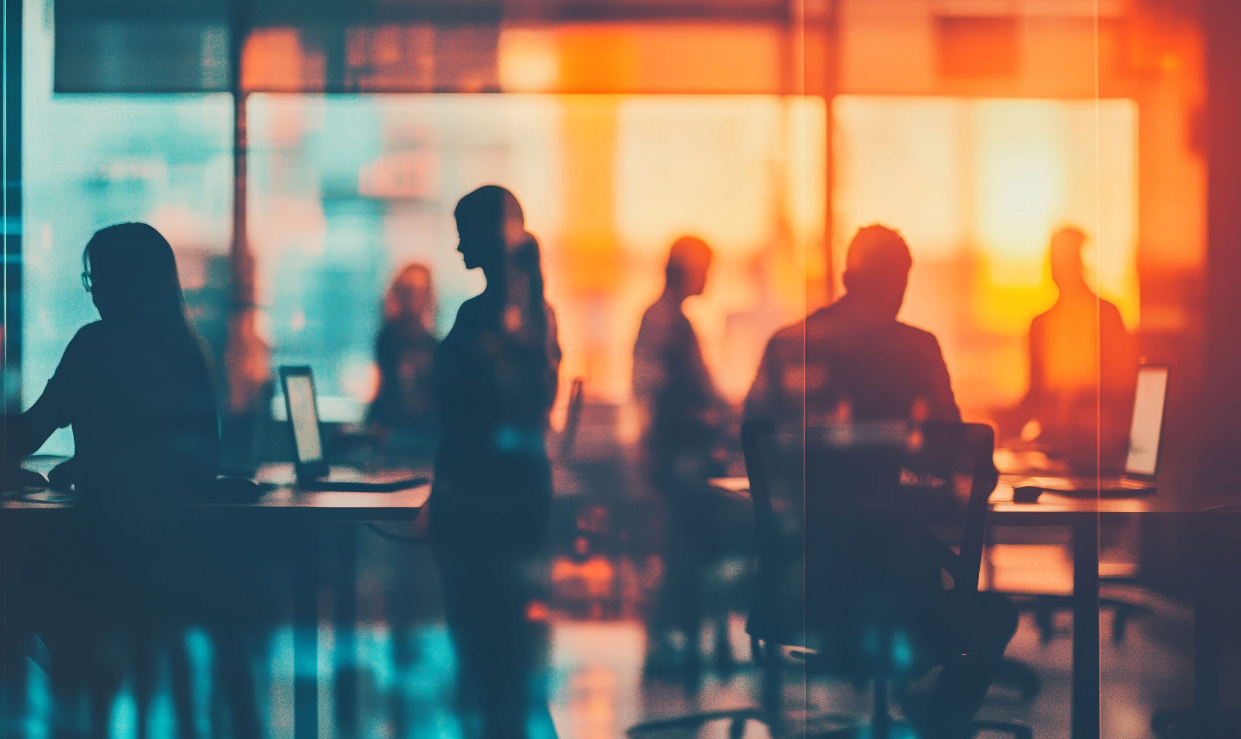 Silhouetted figures collaborating in an office setting viewed through a glass partition with vibrant orange and blue lighting effects, representing DCMM's meeting and collaboration solutions