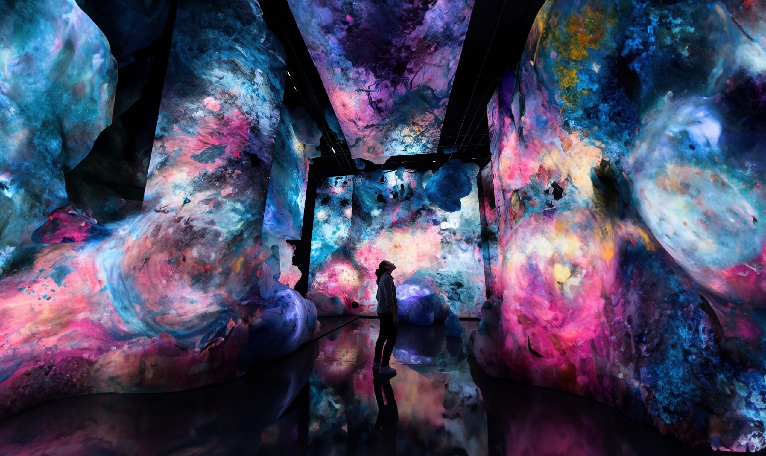 Person standing in a vibrant, immersive art installation with swirling colors resembling a cosmic nebula, showcasing DCMM's immersive experience solutions